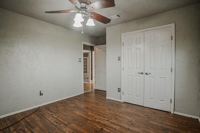 unfurnished bedroom featuring ceiling fan, dark hardwood / wood-style floors, a closet, and a textured ceiling