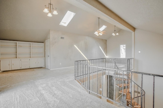 interior space with light carpet, a textured ceiling, a chandelier, and vaulted ceiling with skylight