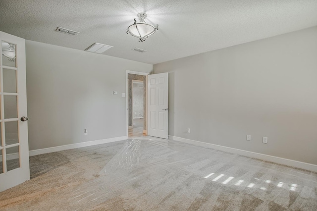 spare room with light carpet and a textured ceiling