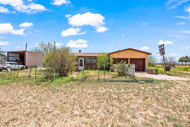 ranch-style home with concrete driveway, stucco siding, central AC, an outbuilding, and a garage