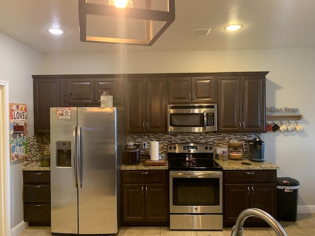 kitchen featuring tasteful backsplash, light stone countertops, appliances with stainless steel finishes, and dark brown cabinetry