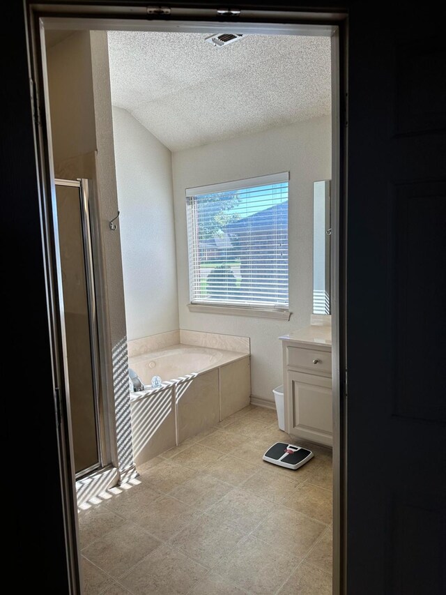 bathroom with vanity, shower with separate bathtub, and a textured ceiling