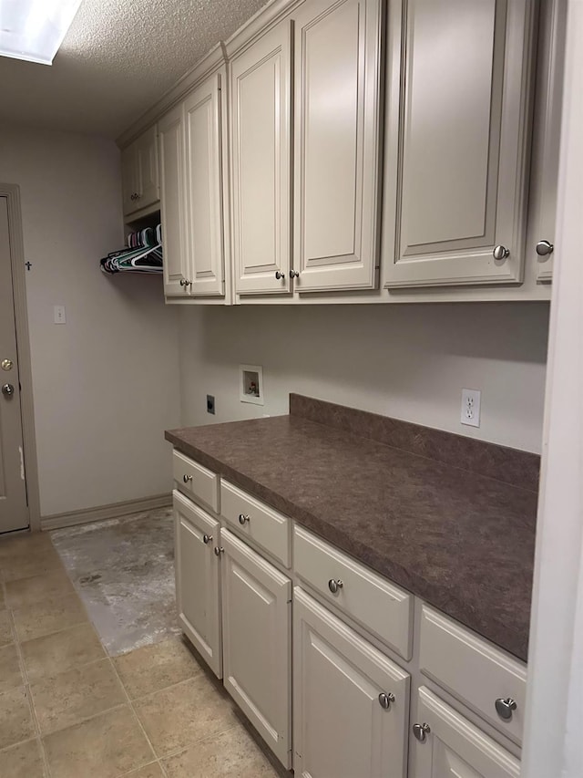 laundry area featuring electric dryer hookup, hookup for a washing machine, cabinets, and a textured ceiling