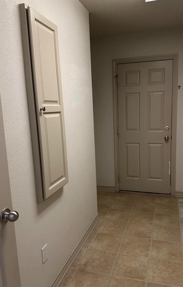 hall featuring a textured ceiling and light tile patterned flooring