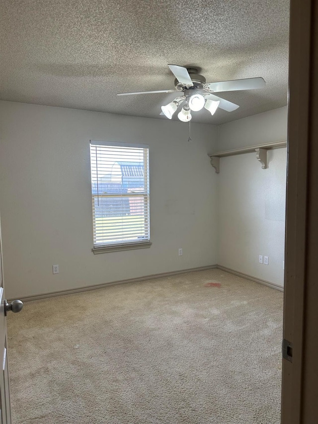 carpeted spare room featuring a textured ceiling and ceiling fan