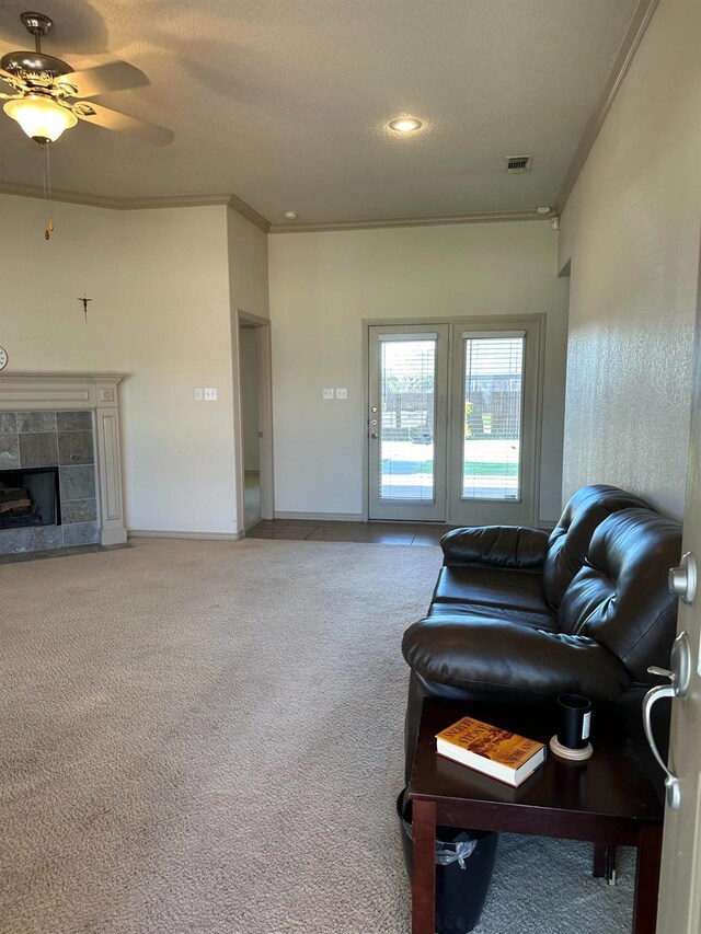 carpeted living room with crown molding, ceiling fan, a fireplace, and a textured ceiling