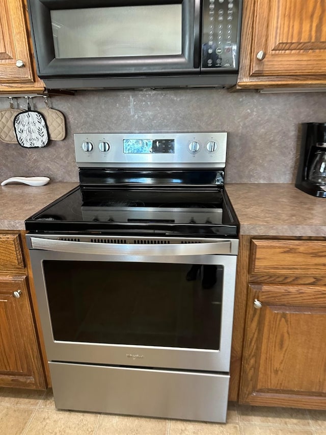 kitchen featuring tasteful backsplash, light tile patterned floors, and electric range