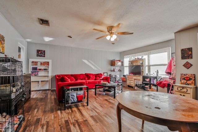 living room featuring ceiling fan, hardwood / wood-style floors, and a textured ceiling