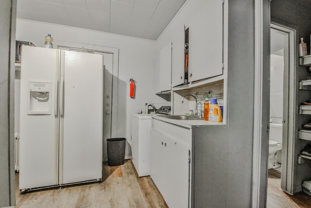 washroom featuring cabinets, sink, light hardwood / wood-style floors, and washer / clothes dryer