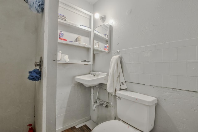 bathroom with toilet, sink, and tile walls