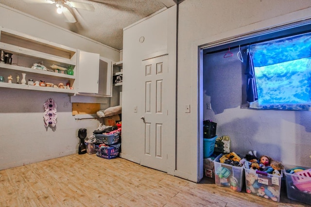 interior space featuring white cabinetry, ceiling fan, light hardwood / wood-style flooring, and a textured ceiling