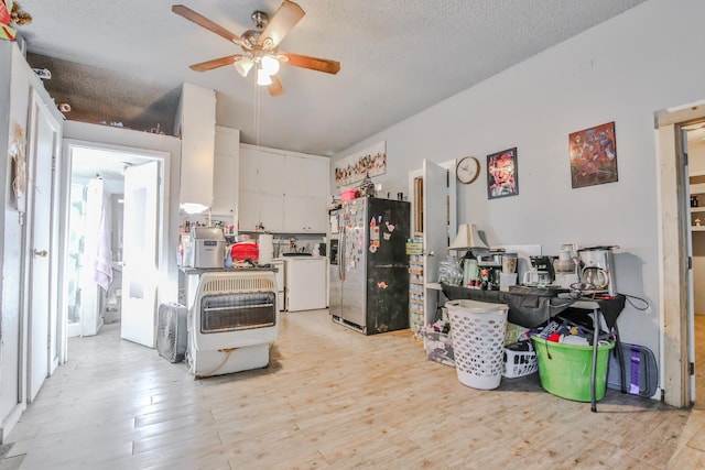 kitchen featuring stainless steel fridge, washer / clothes dryer, light hardwood / wood-style flooring, and white cabinets