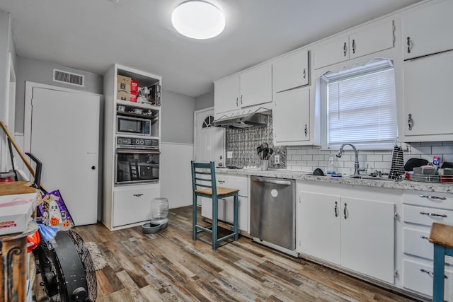 kitchen with sink, light hardwood / wood-style flooring, appliances with stainless steel finishes, decorative backsplash, and white cabinets