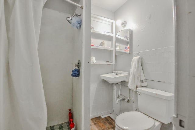 bathroom with wood-type flooring, toilet, a shower with shower curtain, and tile walls