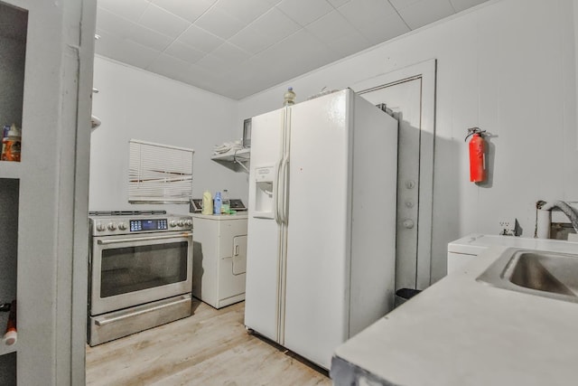 kitchen featuring washer / dryer, sink, white refrigerator with ice dispenser, electric range, and light wood-type flooring