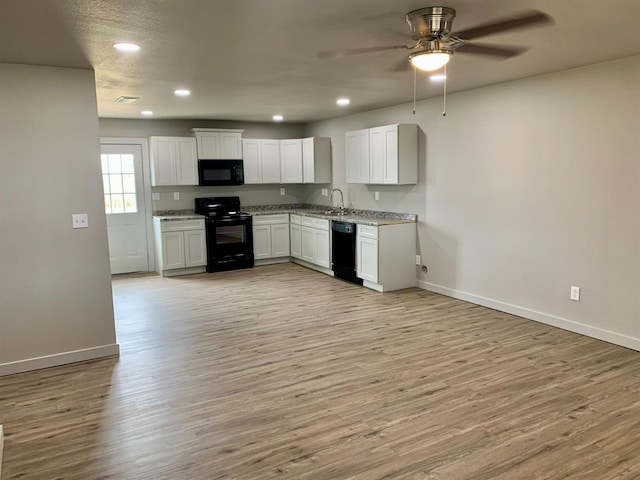 kitchen featuring sink, black appliances, light hardwood / wood-style floors, and white cabinets