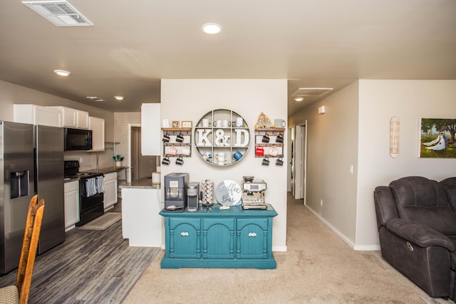 kitchen featuring white cabinetry, dark stone counters, carpet floors, and black appliances