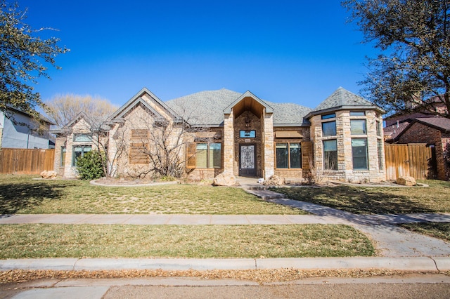 view of front of house featuring stone siding, a front lawn, fence, and brick siding