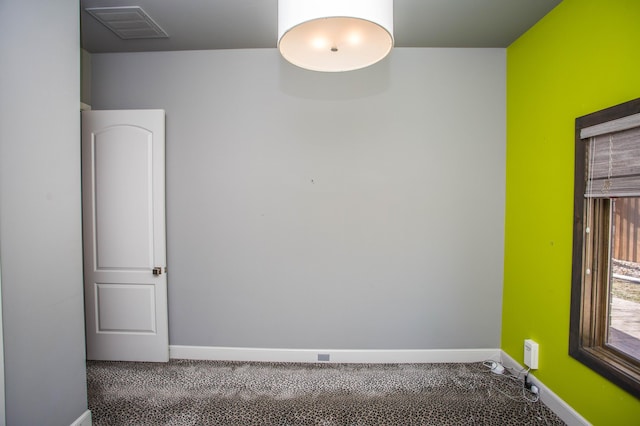 empty room featuring carpet, visible vents, and baseboards