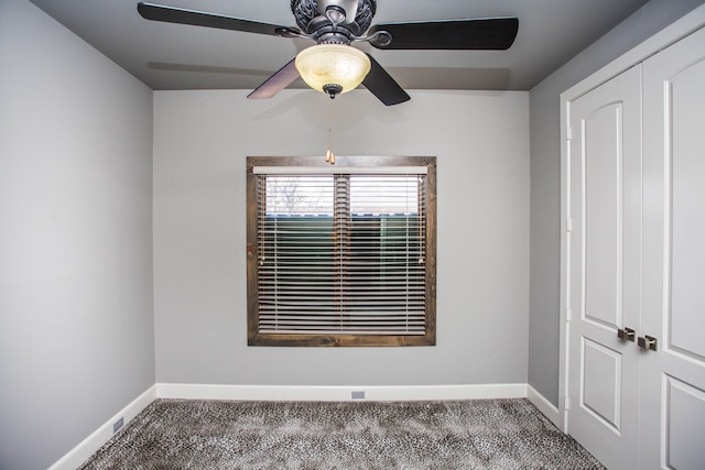 carpeted empty room featuring ceiling fan and baseboards