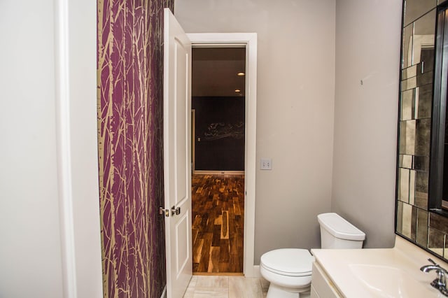 bathroom featuring toilet, wood finished floors, vanity, and baseboards