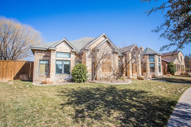 view of front of home featuring stone siding, brick siding, fence, and a front lawn