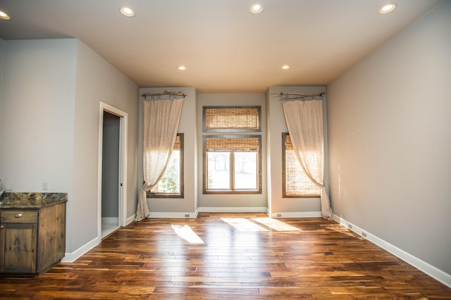 spare room featuring baseboards, dark wood-type flooring, and recessed lighting