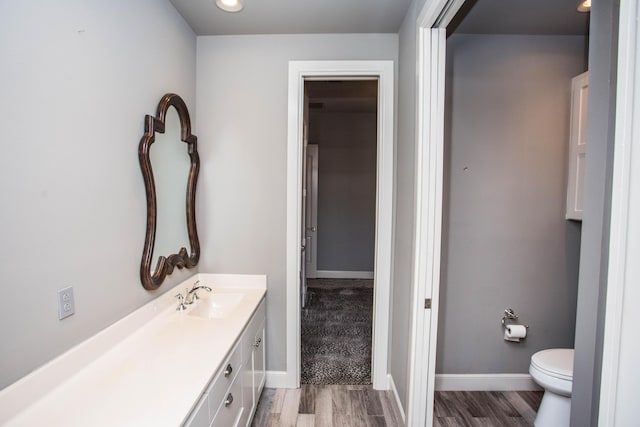 bathroom with toilet, baseboards, and wood finished floors