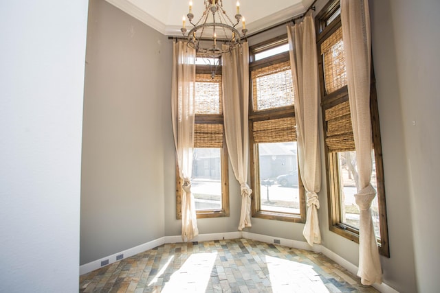 empty room featuring crown molding, baseboards, and an inviting chandelier