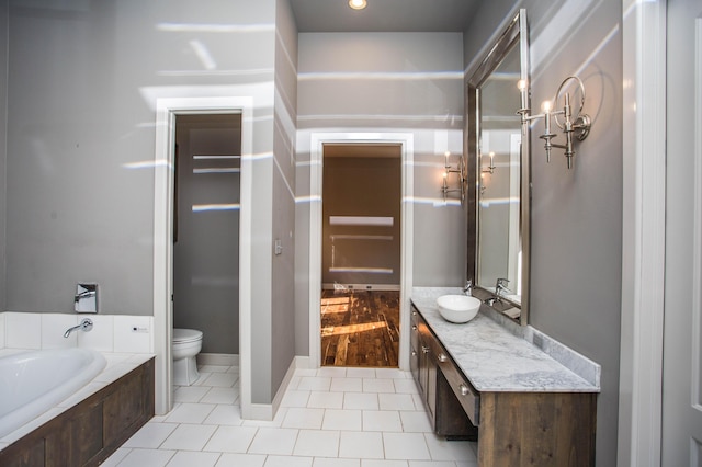 bathroom with a tub, vanity, toilet, and tile patterned floors