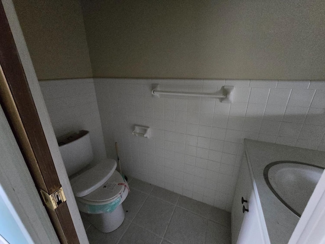 bathroom featuring tile patterned floors, toilet, vanity, and tile walls