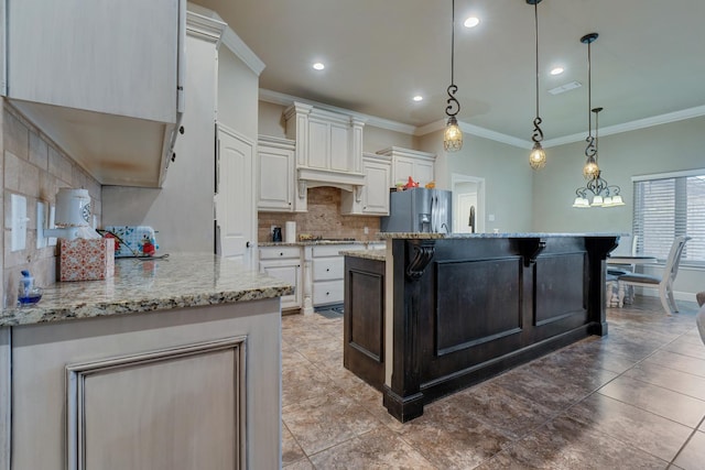 kitchen with white cabinets, hanging light fixtures, stainless steel fridge with ice dispenser, light stone countertops, and a spacious island