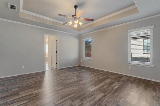 empty room with dark hardwood / wood-style floors, ceiling fan, a tray ceiling, and crown molding