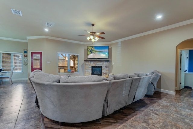 living room with crown molding, a stone fireplace, and ceiling fan