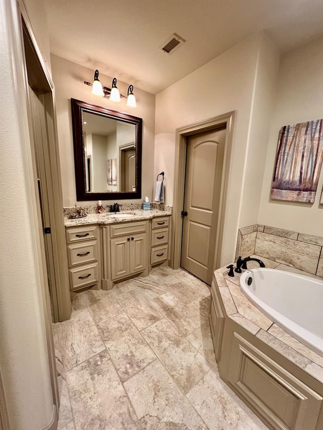 bathroom featuring a relaxing tiled tub and vanity