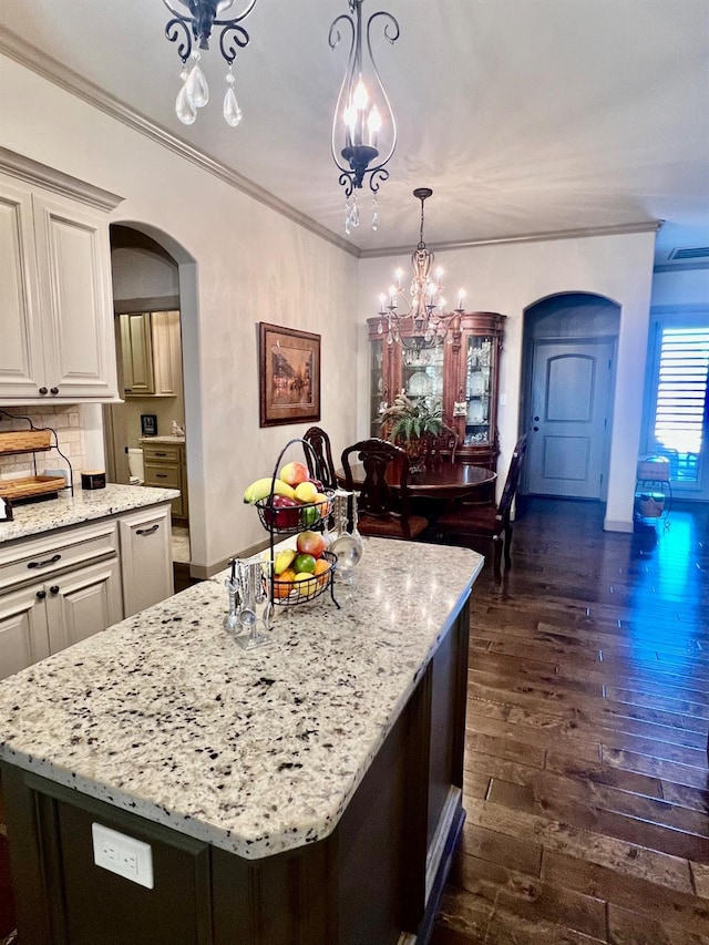 kitchen featuring tasteful backsplash, crown molding, hanging light fixtures, dark hardwood / wood-style flooring, and a kitchen island