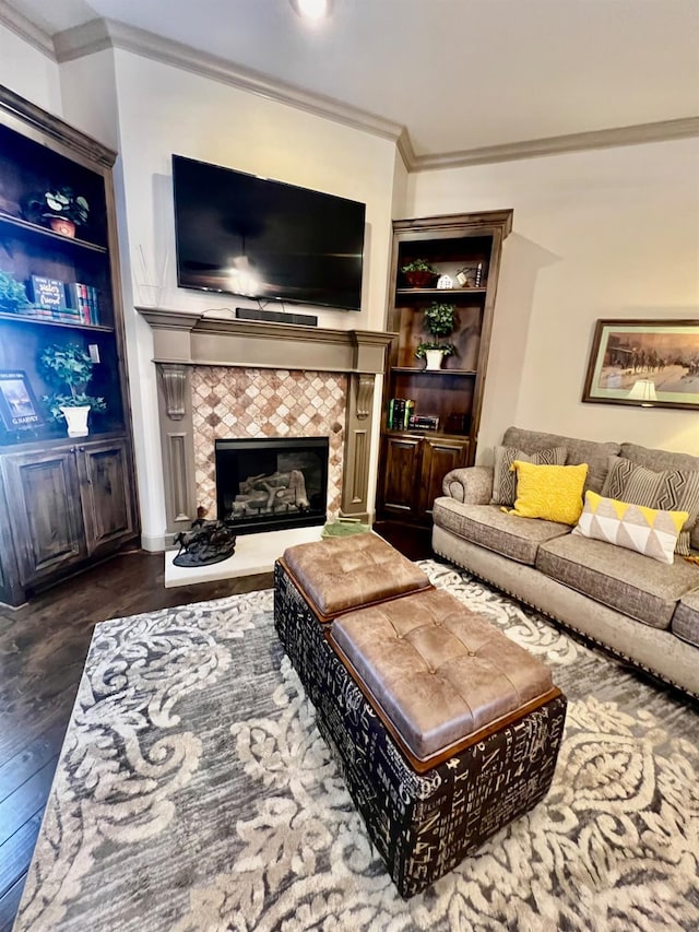 living room with built in shelves, ornamental molding, dark hardwood / wood-style floors, and a tile fireplace