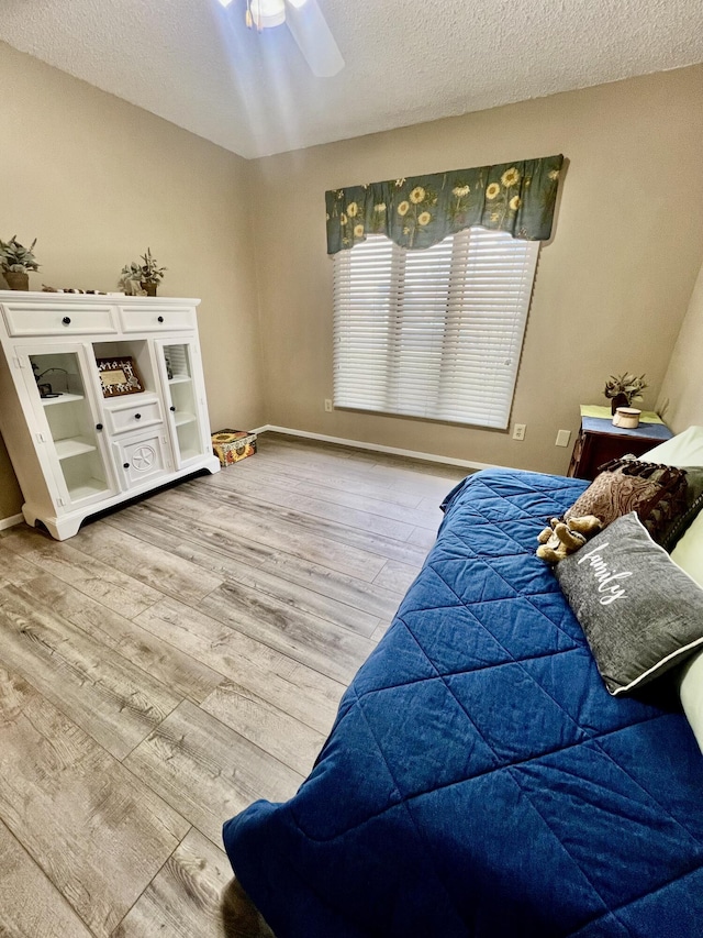 bedroom with ceiling fan, a textured ceiling, and wood finished floors