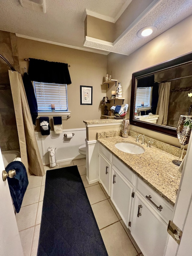 full bathroom featuring a textured ceiling, toilet, vanity, ornamental molding, and tile patterned floors