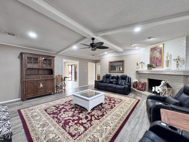 living room featuring a textured ceiling, lofted ceiling with beams, light wood-type flooring, and visible vents