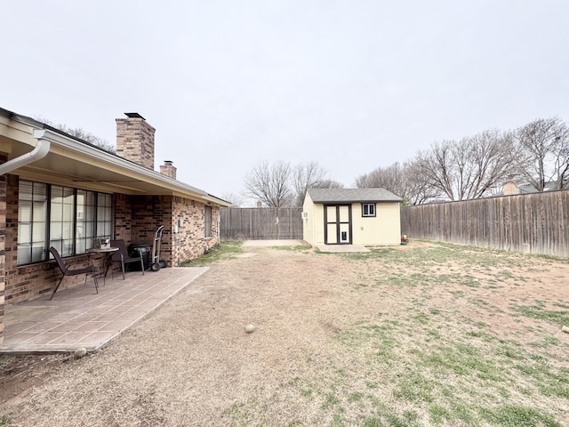 view of yard featuring an outbuilding, a storage unit, a patio area, and a fenced backyard