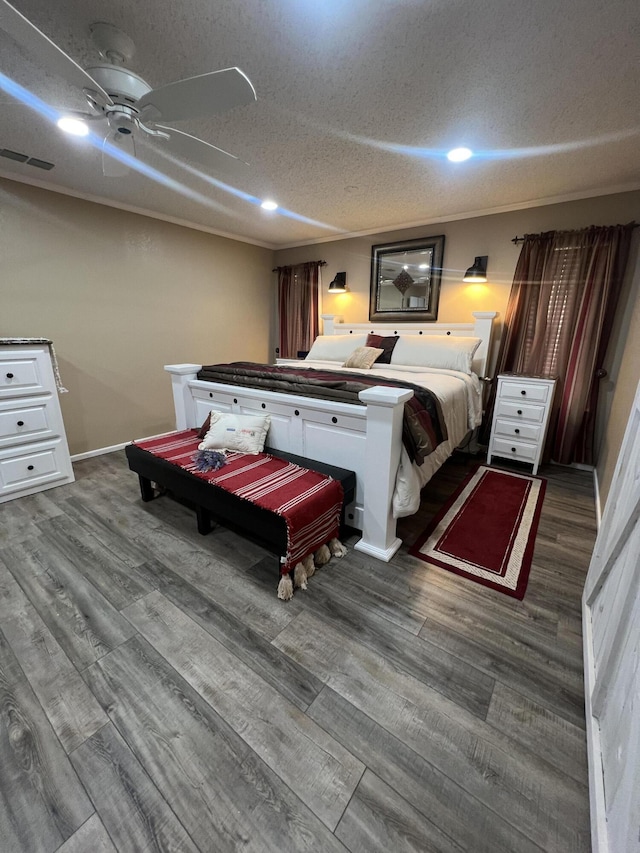 bedroom with a textured ceiling, wood finished floors, visible vents, and baseboards