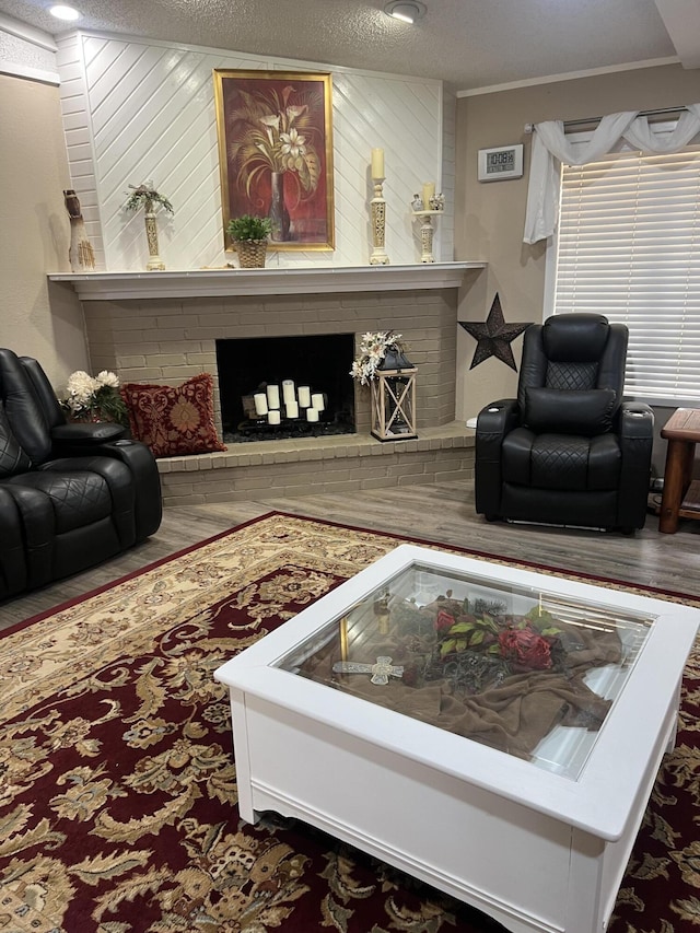 living room with crown molding, a fireplace, a textured ceiling, and wood finished floors