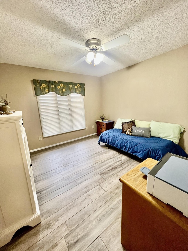 bedroom with a textured ceiling, wood finished floors, a ceiling fan, and baseboards