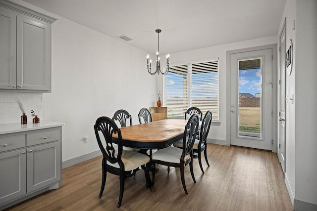 dining room with a chandelier, visible vents, light wood finished floors, and baseboards