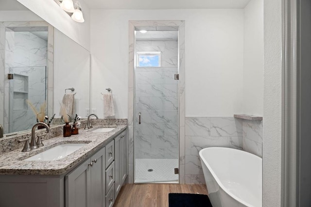 bathroom with a sink, a marble finish shower, wood finished floors, and a freestanding tub