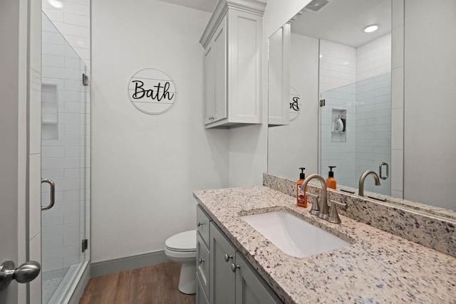 bathroom featuring a shower stall, toilet, wood finished floors, and visible vents