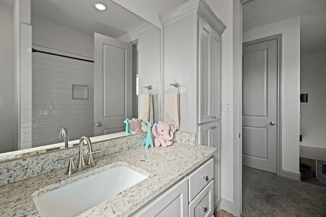 full bath featuring vanity, recessed lighting, baseboards, and tiled shower