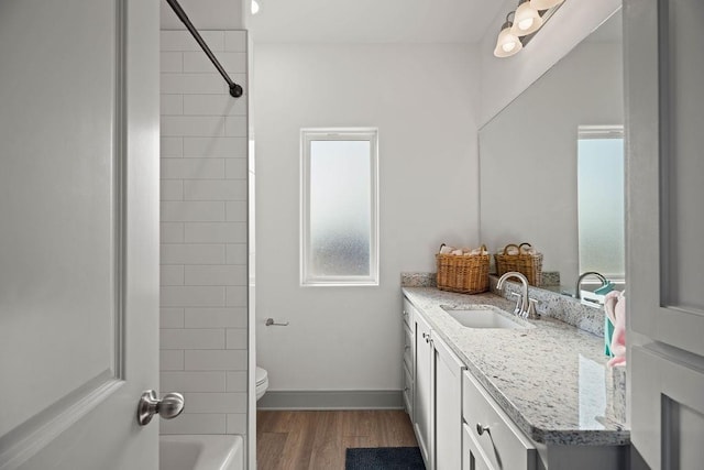 bathroom with baseboards, toilet, shower / bathtub combination, wood finished floors, and vanity
