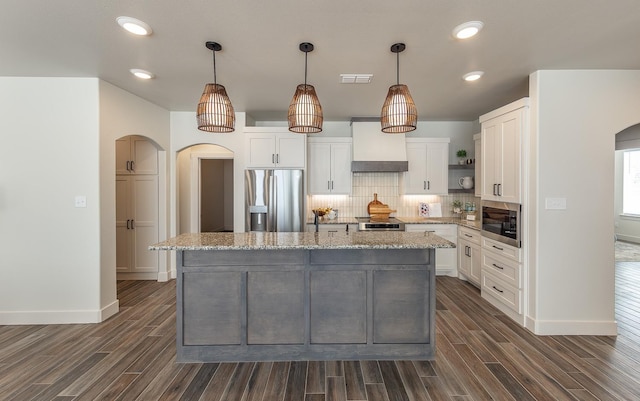 kitchen featuring visible vents, premium range hood, arched walkways, stainless steel appliances, and tasteful backsplash